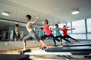 Group of women on treadmills performing synchronized cardio in a bright fitness studio.